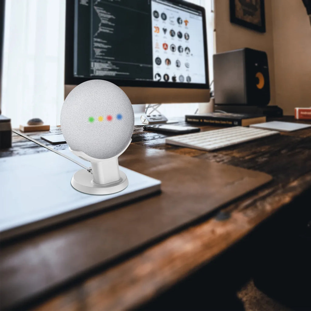 Black or white plastic stand holding a Google Home Mini voice assistant on a desk.