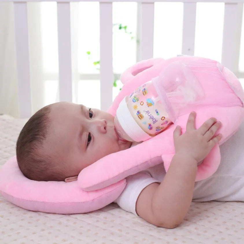 Pink plush baby feeding pillow on a carpet, showing its 30cm by 42cm size and soft texture.