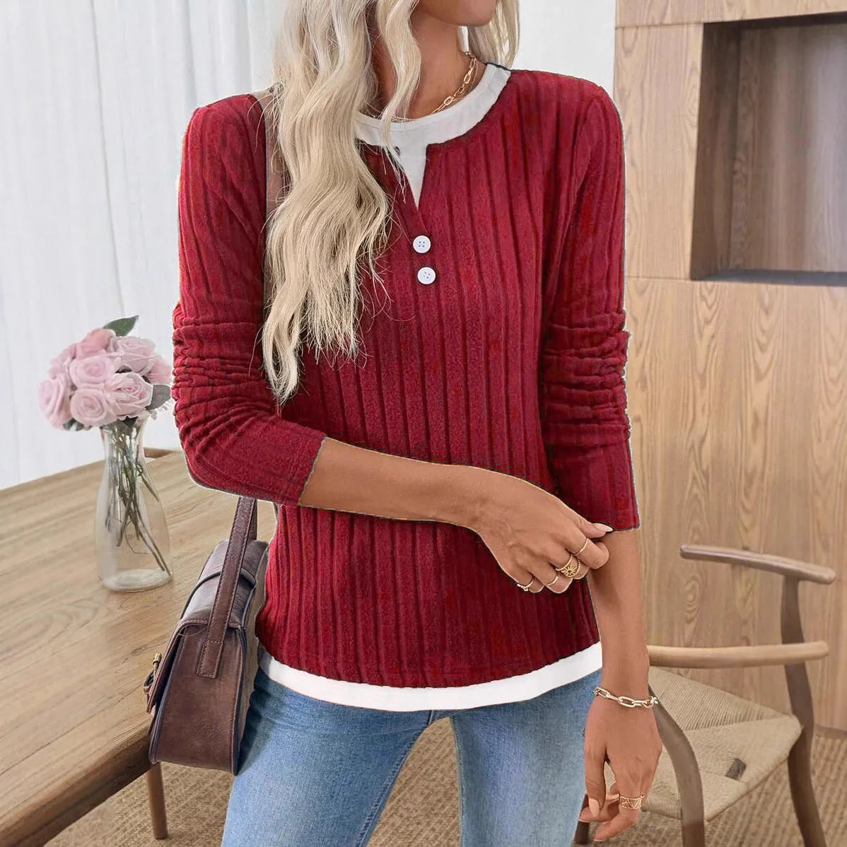 Women's black fake two-piece pullover sweater with round neck, button, and long sleeves on a hanger.