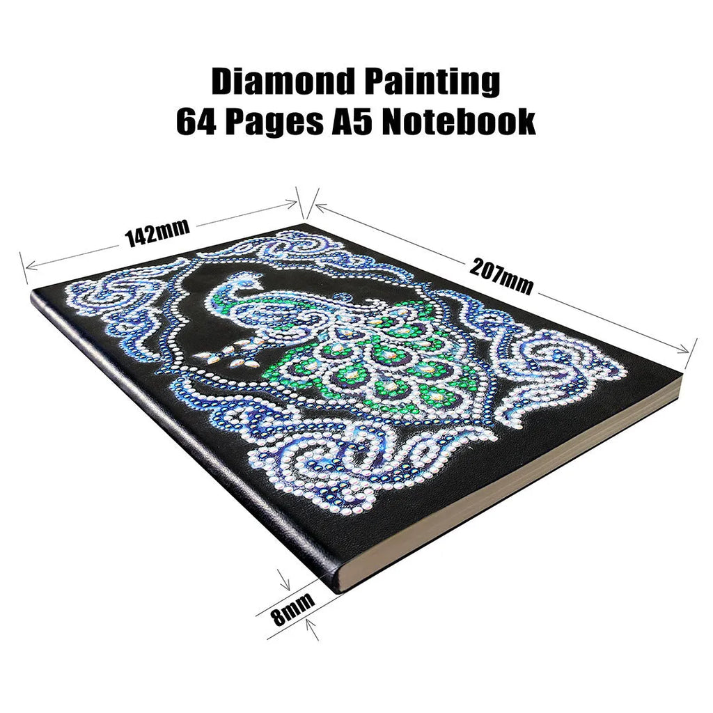 A5 notebook with a sparkling peacock diamond painting on the cover, shown next to open lined pages.