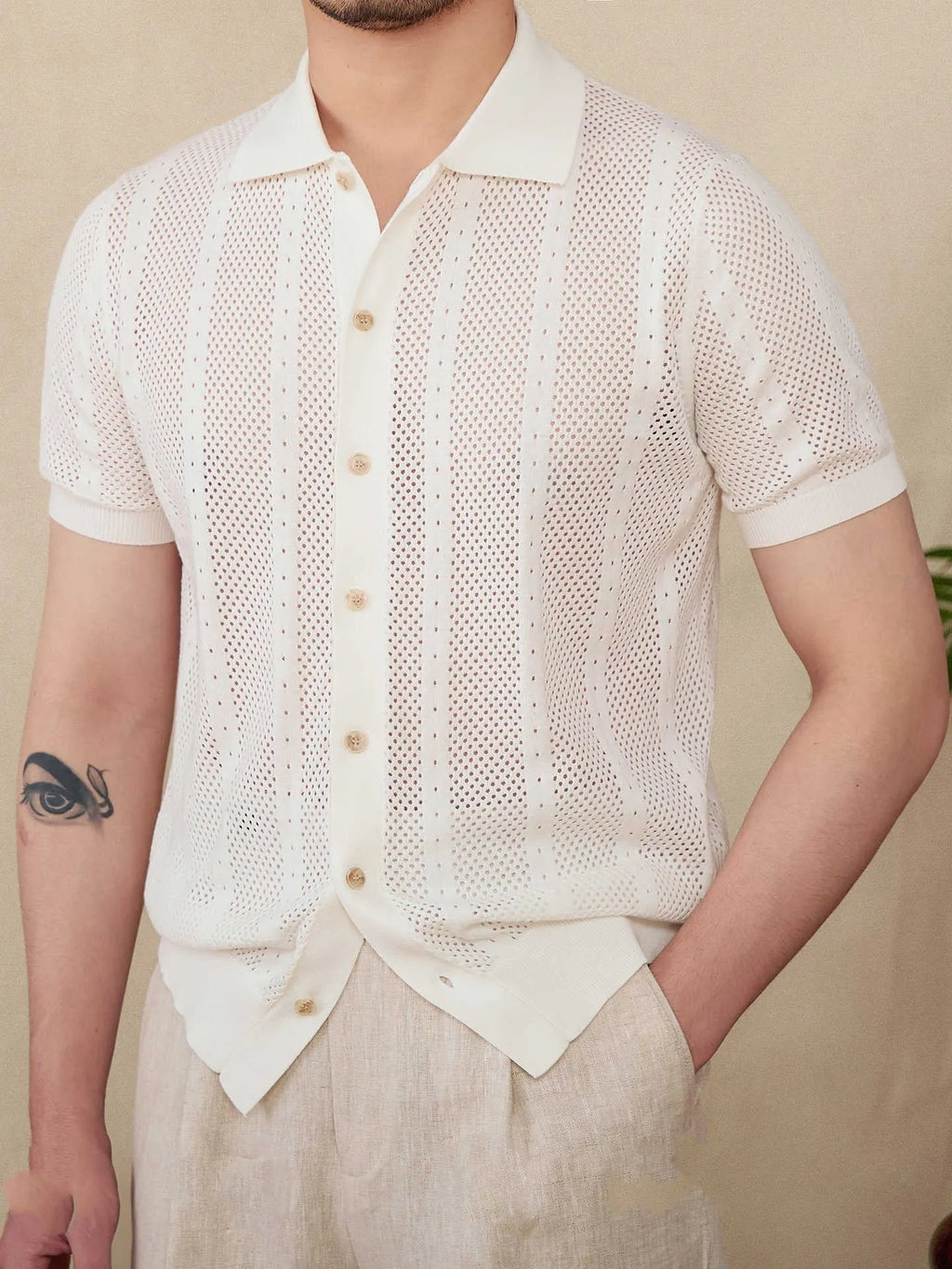 Man wearing a beige striped short sleeve cotton cardigan shirt with a lapel collar.
