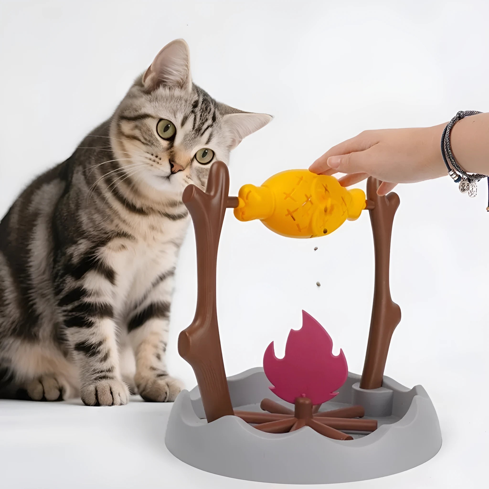 Barbecue-style rolling cat feeder toy with treat compartments, measuring 30cm cubed on a floor.