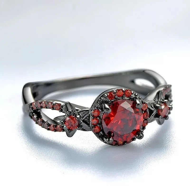 Black gold plated copper ring with round red zircon stone and wave-shaped band on finger