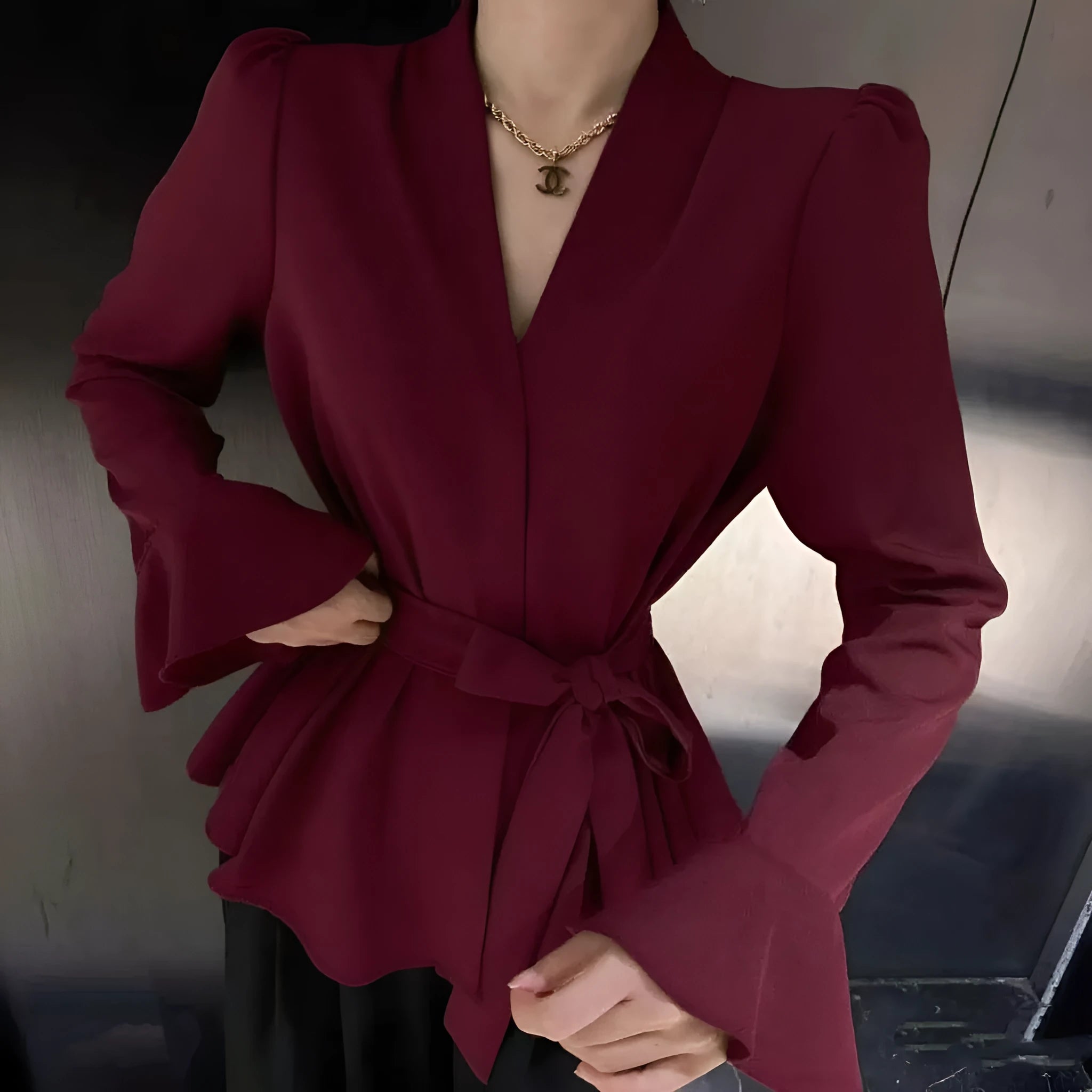 Women's black long sleeve shirt with an irregular collar and a tie closure at the neck.