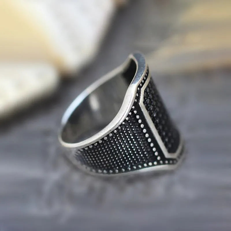 Black alloy ring with copper metal inlay and sparkling zircon stone accents on a finger.