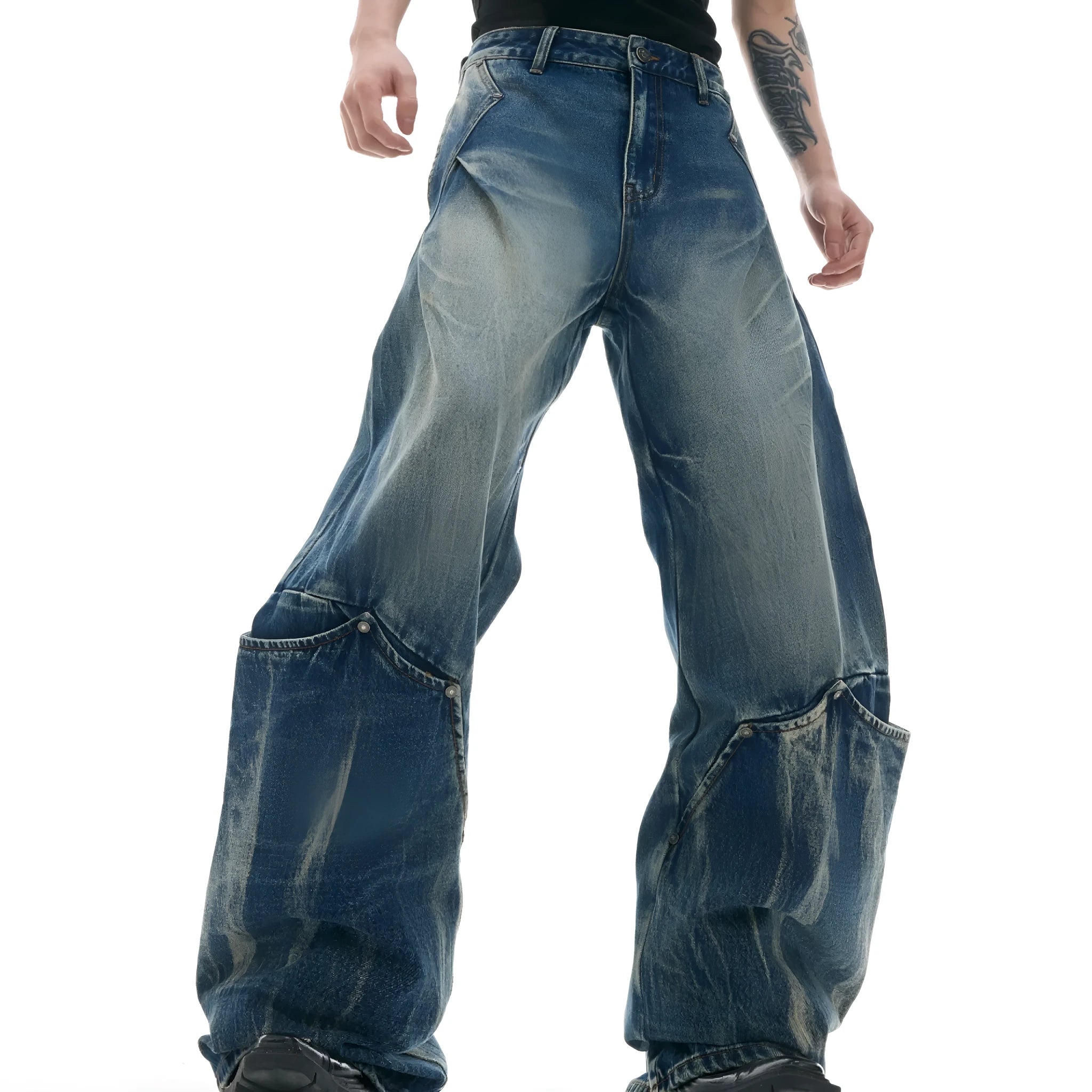Man wearing verdant blue loose-fit jeans with a curved knife burst pattern on the thighs.