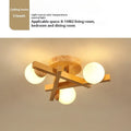 Modern Nordic-style wooden ceiling light fixture with three adjustable lamp heads mounted on a living room ceiling.