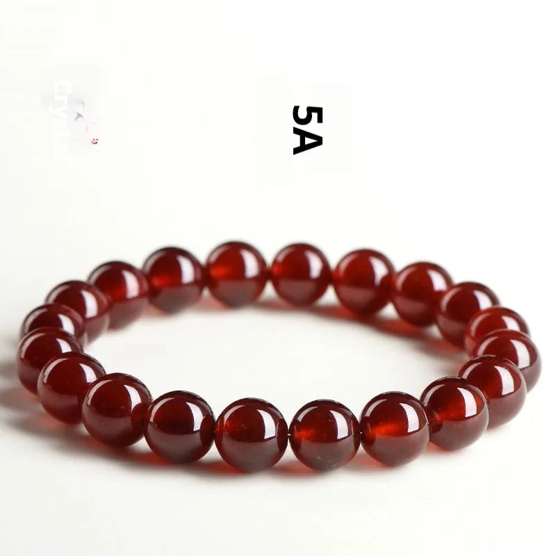 Unisex orange red garnet ball bracelet with crystal beads and a metal Ruyi charm on a wrist.