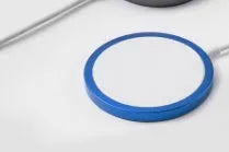 Silver metal Magsafe-compatible magnetic wireless charger for iPhone on a wooden table