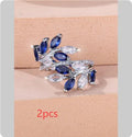 Adjustable open-ended copper ring with leaf design and central blue zircon stone on a finger.