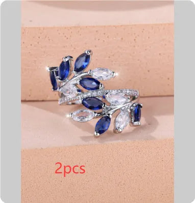 Adjustable open-ended copper ring with leaf design and central blue zircon stone on a finger.