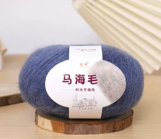 A ball of mohair yarn in a selected colour next to a hand-woven scarf example, showcasing the DIY kit.