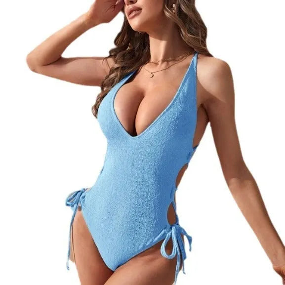 Women's solid colour one-piece swimsuit with a large open back design and central fabric tether detail.
