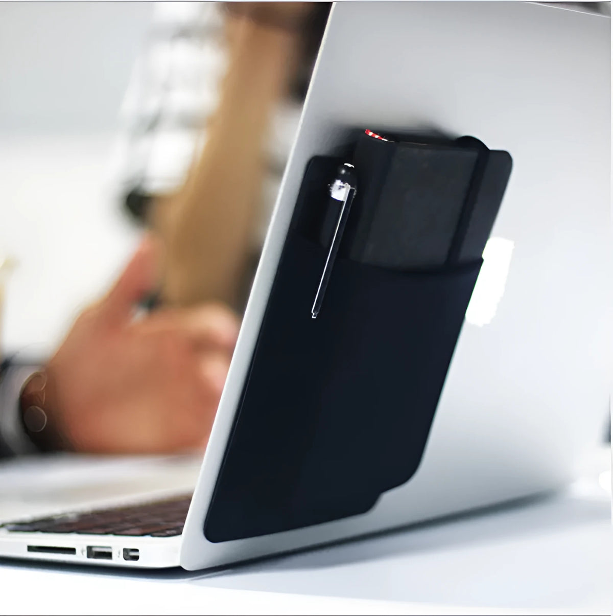 Black adhesive Lycra laptop back storage bag 15x12cm with pen loop, attached to laptop showing items inside