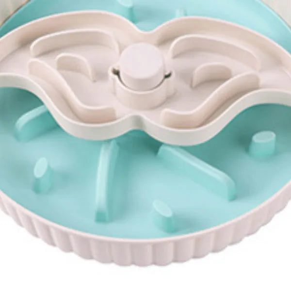 Grey pet bowl with a rotating windmill-pattern silicone licking mat for slow feeding on a kitchen floor.