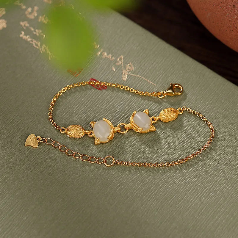 Close-up of a women's silver bracelet with a detailed fox charm and a round stone bead on an adjustable chain.
