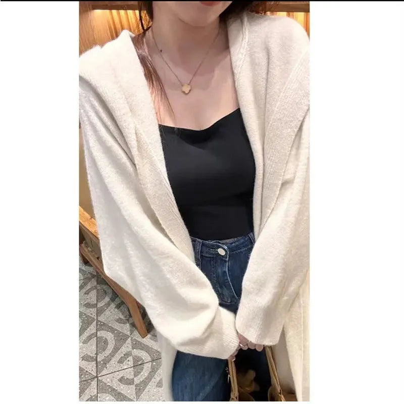 A woman wearing a long, loose, hooded knitted cardigan in a solid colour, demonstrating its below-the-knee length.