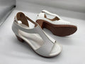 Women's beige peep toe wedge sandals with a buckle strap, shown on a foot.