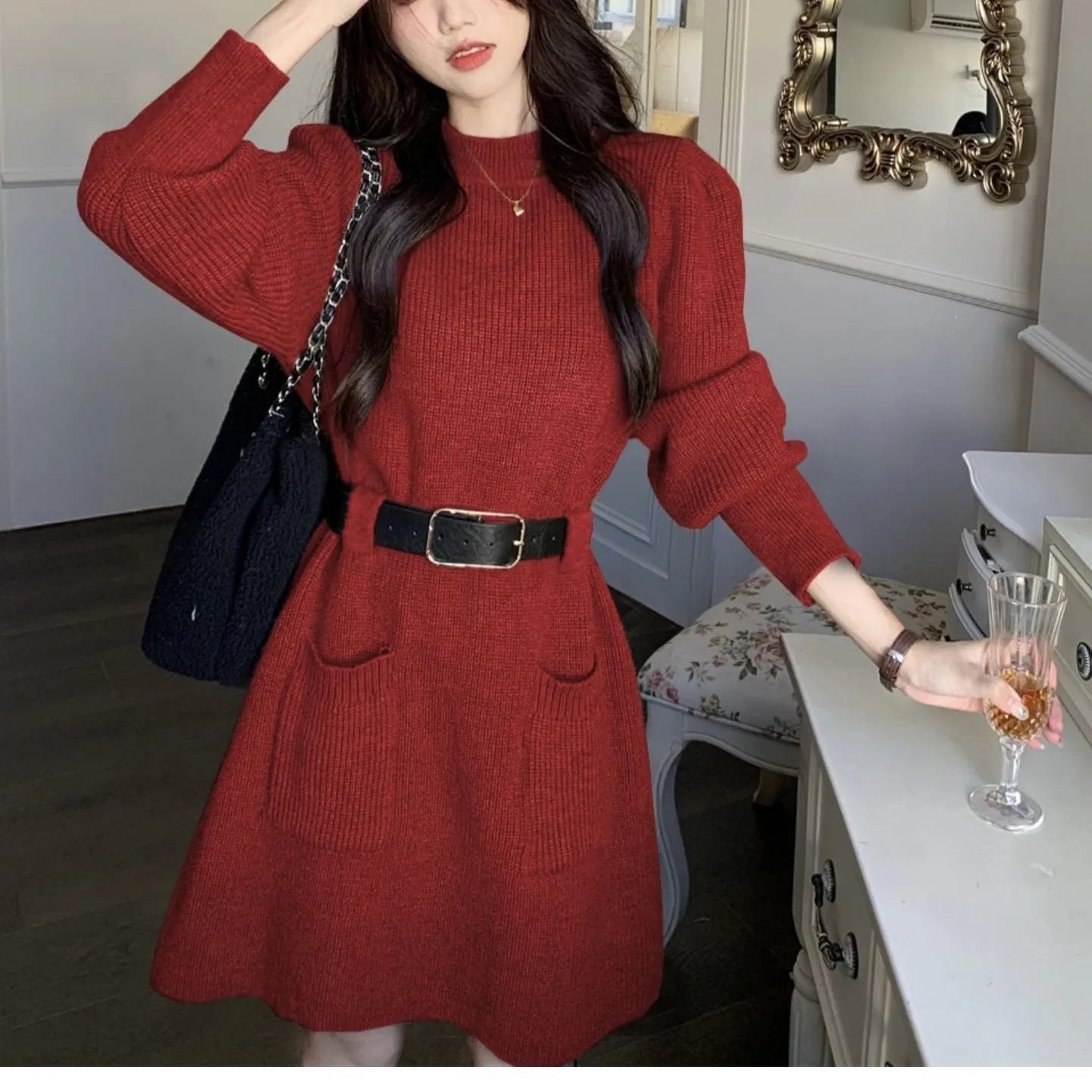 Long sleeve loose knitted dress for women in beige with a black belt, shown on a hanger.
