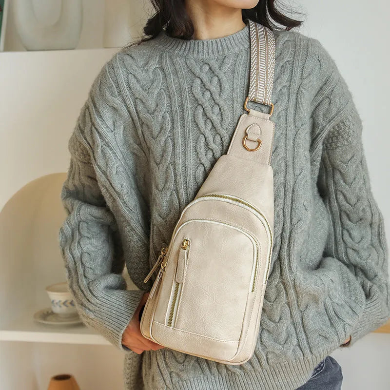Soft brown women's crossbody chest bag with an open front pocket and decorative stitching.