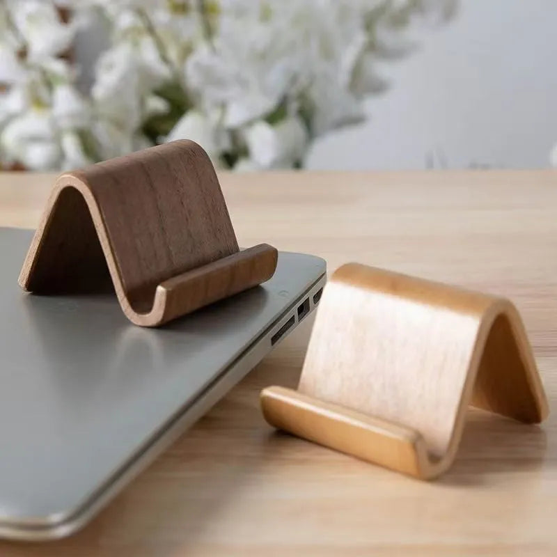 Walnut wood mobile phone bracket on a desk holding a smartphone upright for handsfree viewing