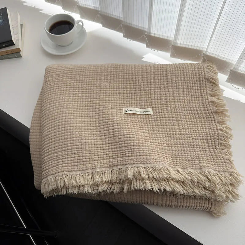 Four-layer gauze cotton blanket with tassel trim in avocado green, laid flat.