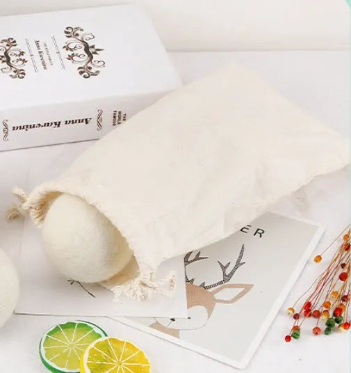 Set of 100% wool felt laundry drying balls in various sizes next to a plain cotton storage bag.