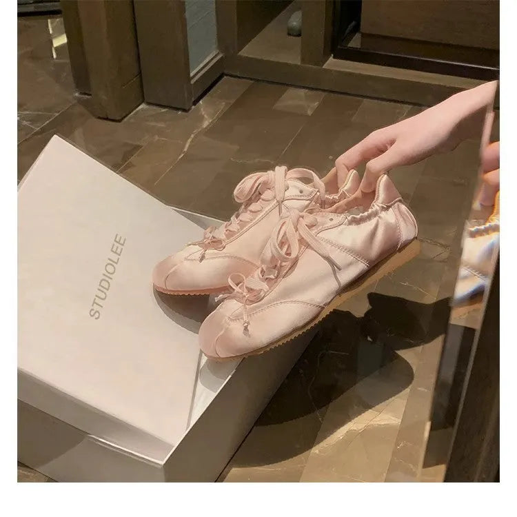 Women's silver grey satin ballet flat shoes with front lace-up design and round toe.