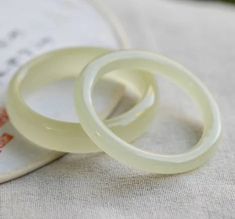 Ice silk jade round bar bracelet on a wrist, showing its smooth, continuous loop and polished stone finish.