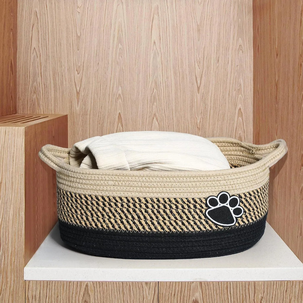 Light beige handmade woven cotton rope storage basket with a wooden handle on a wooden floor.