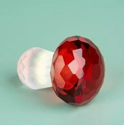 Handcrafted white crystal mushroom decoration in four colours on a wooden surface.