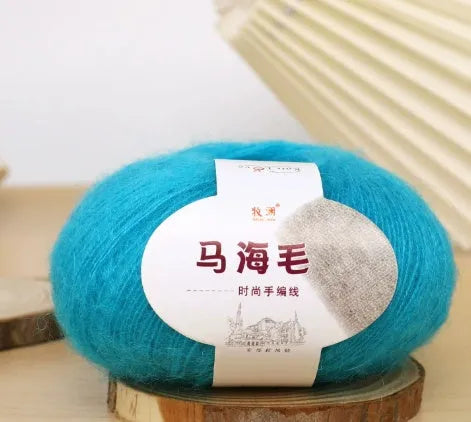 A ball of mohair yarn in a selected colour next to a hand-woven scarf example, showcasing the DIY kit.