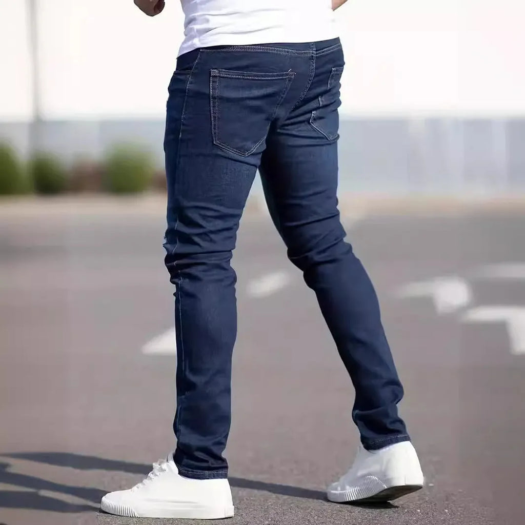 Man wearing dark blue slim fit skinny jeans with a mid-rise waist and zipper fly.