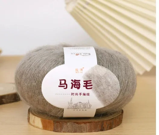 A ball of mohair yarn in a selected colour next to a hand-woven scarf example, showcasing the DIY kit.