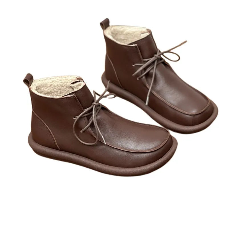 Women's black cowhide winter boots with flat heel and round toe on neutral background