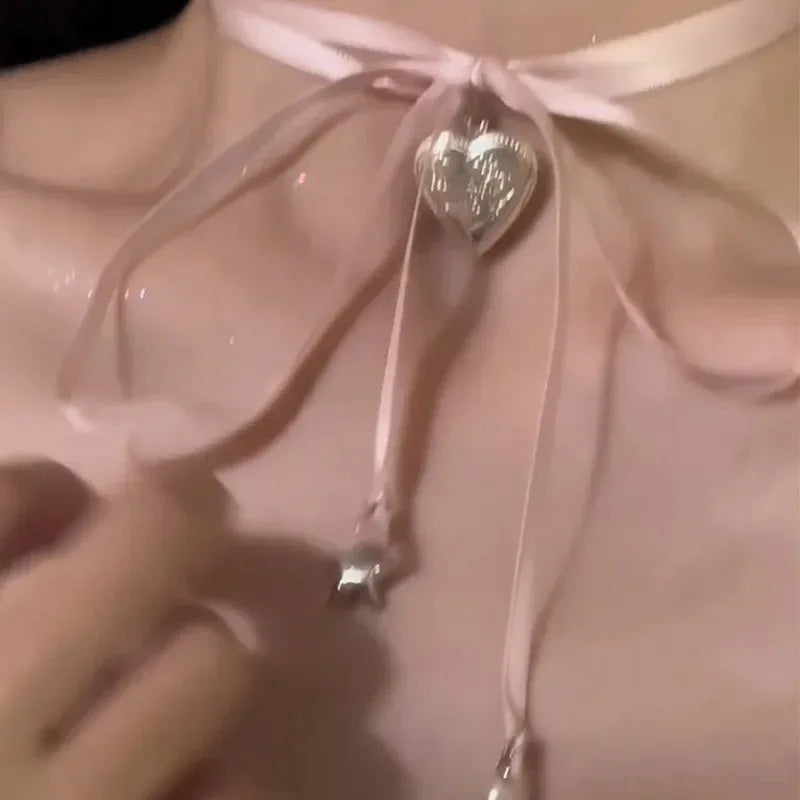 Close-up of a women's alloy fashion necklace with a ribbon love pendant on a dainty clavicle chain.