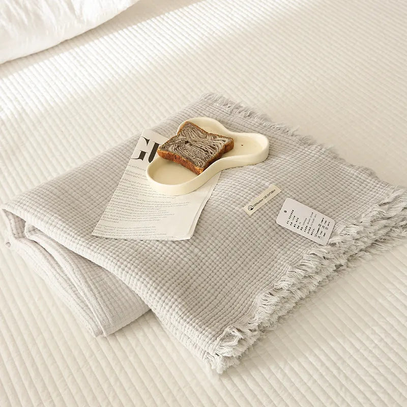 Four-layer gauze cotton blanket with tassel trim in avocado green, laid flat.
