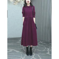 Purplish red women's long-sleeve maxi dress with extra-long cuffs and urban commute style on a hanger.