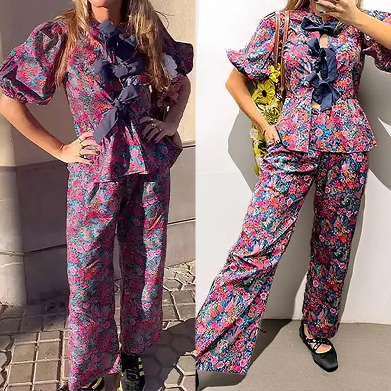 Women's floral printed trousers suit with a tie-neck blouse featuring puff sleeves and matching trousers.