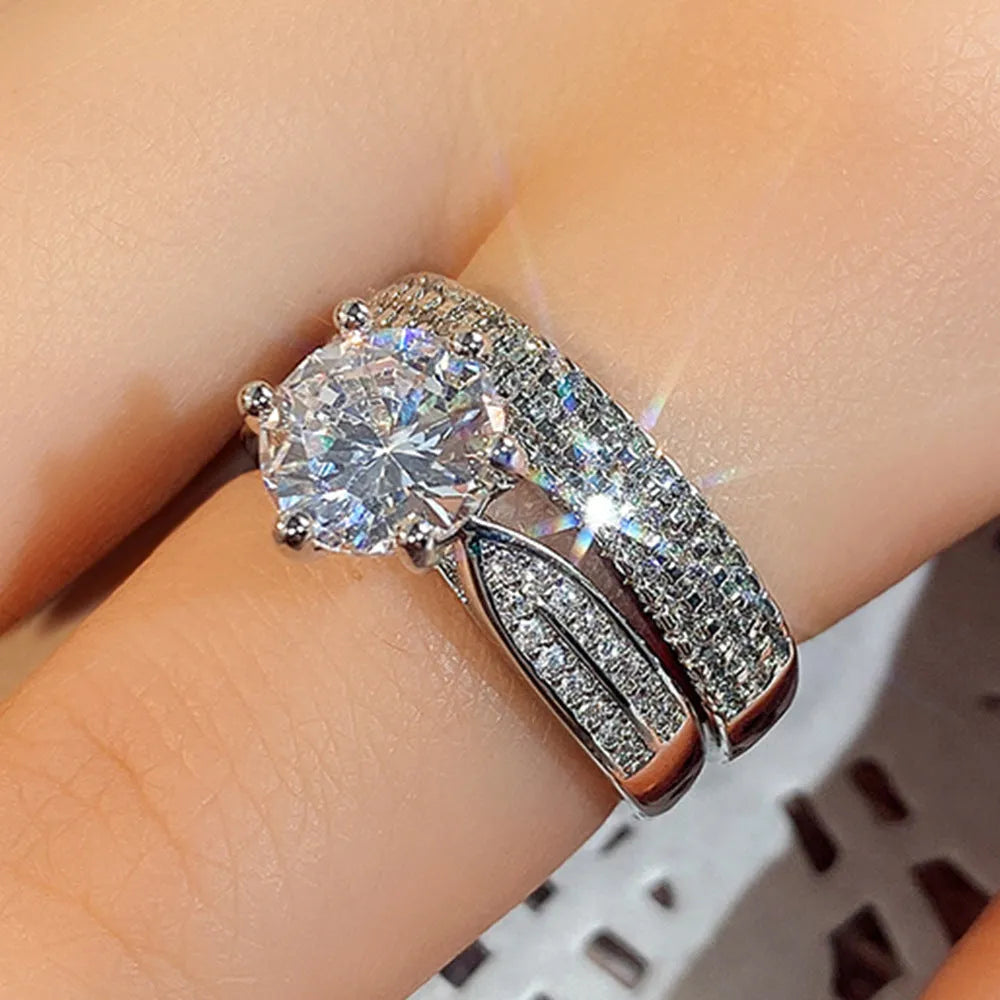A white gold-coloured geometric bracelet ring with an integrated round element on a model's finger.