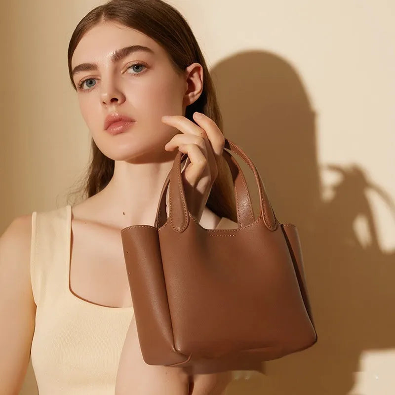 Genuine cattlehide leather retro crossbody bucket bag in black showing external slit pocket and sewing thread detail.