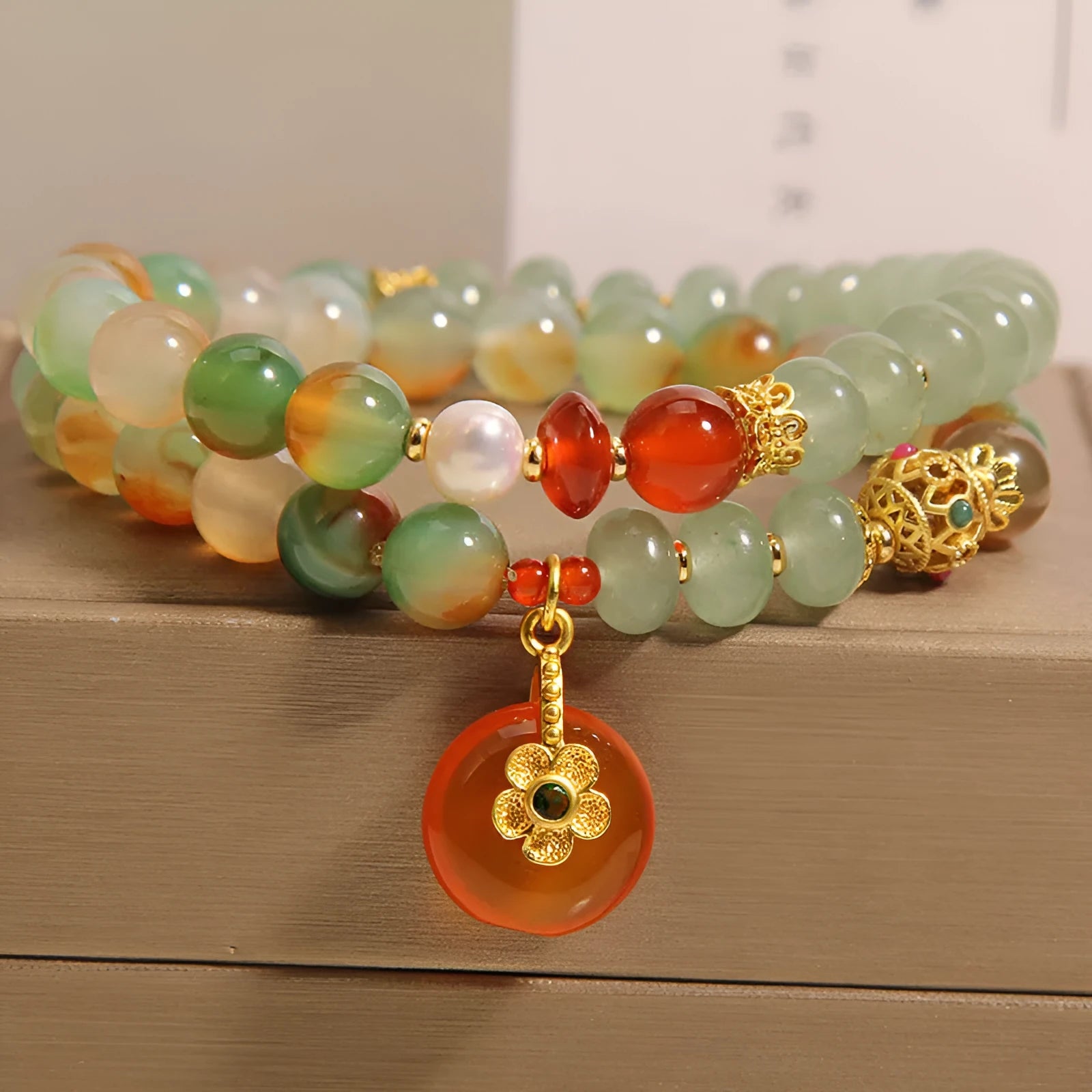 Women's peacock green agate double ring bracelet with safety buckle and rhinestones on a wrist.