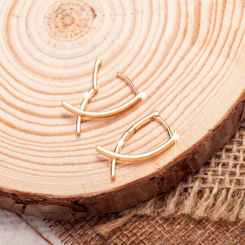 Rose gold cross shaped earrings on a plain background.