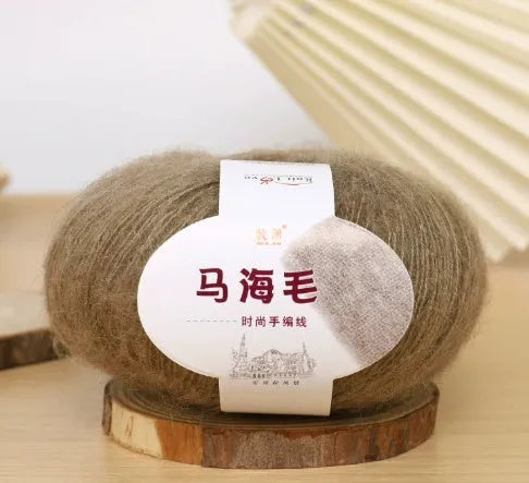 A ball of mohair yarn in a selected colour next to a hand-woven scarf example, showcasing the DIY kit.
