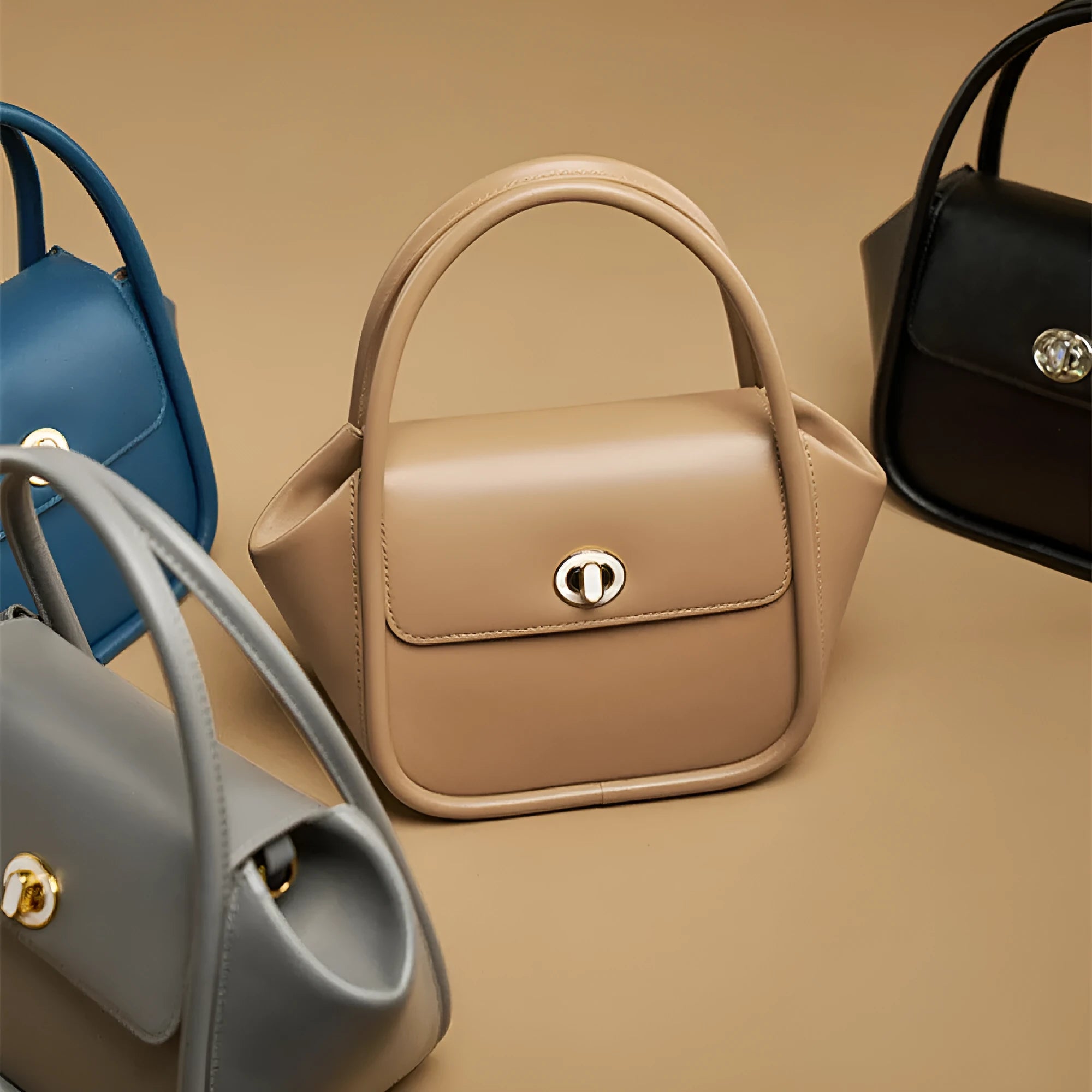 A women's leather wing-shaped tote bag with a metal latch, shown in blue on a cross-body strap.