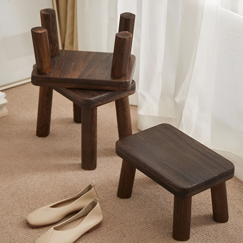 Solid wood shoe changing stool with a distressed finish and angular bracket frame.