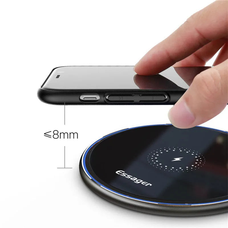 Black aluminium 15W Qi wireless fast charger for phones on a wooden desk.