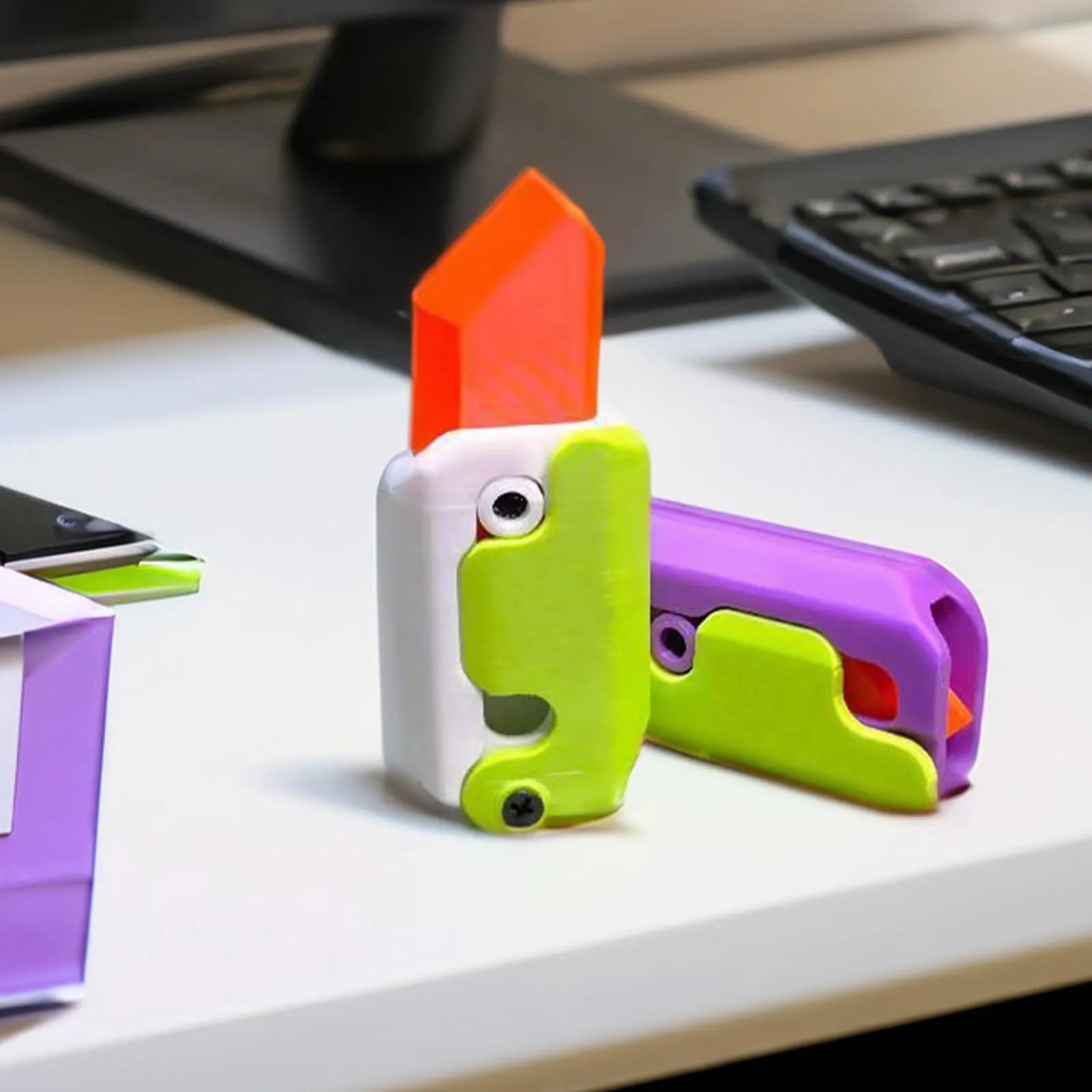 3D printed plastic gravity carrot knife fidget toy in orange, purple, and green colours.