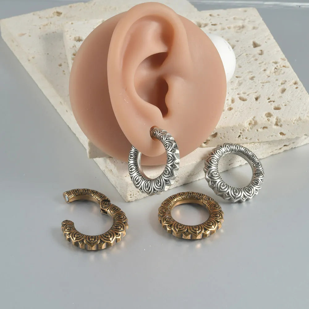 Pair of large antique silver dragon-shaped hollow-out earrings with geometric design on a plain background.