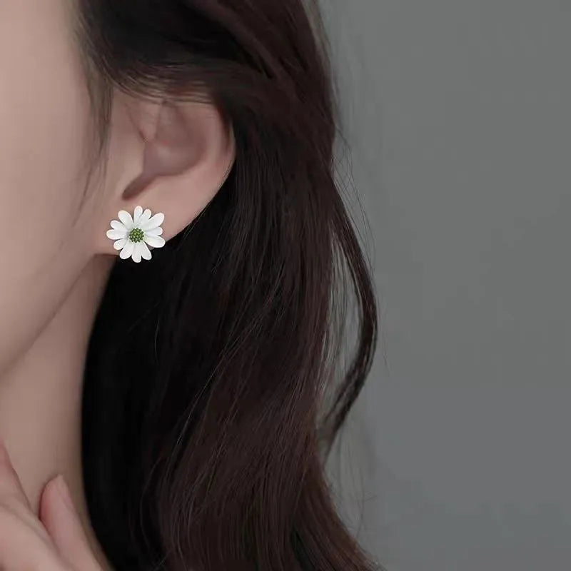 Close-up of colourful alloy flower stud earrings showing white and green two-tone design.